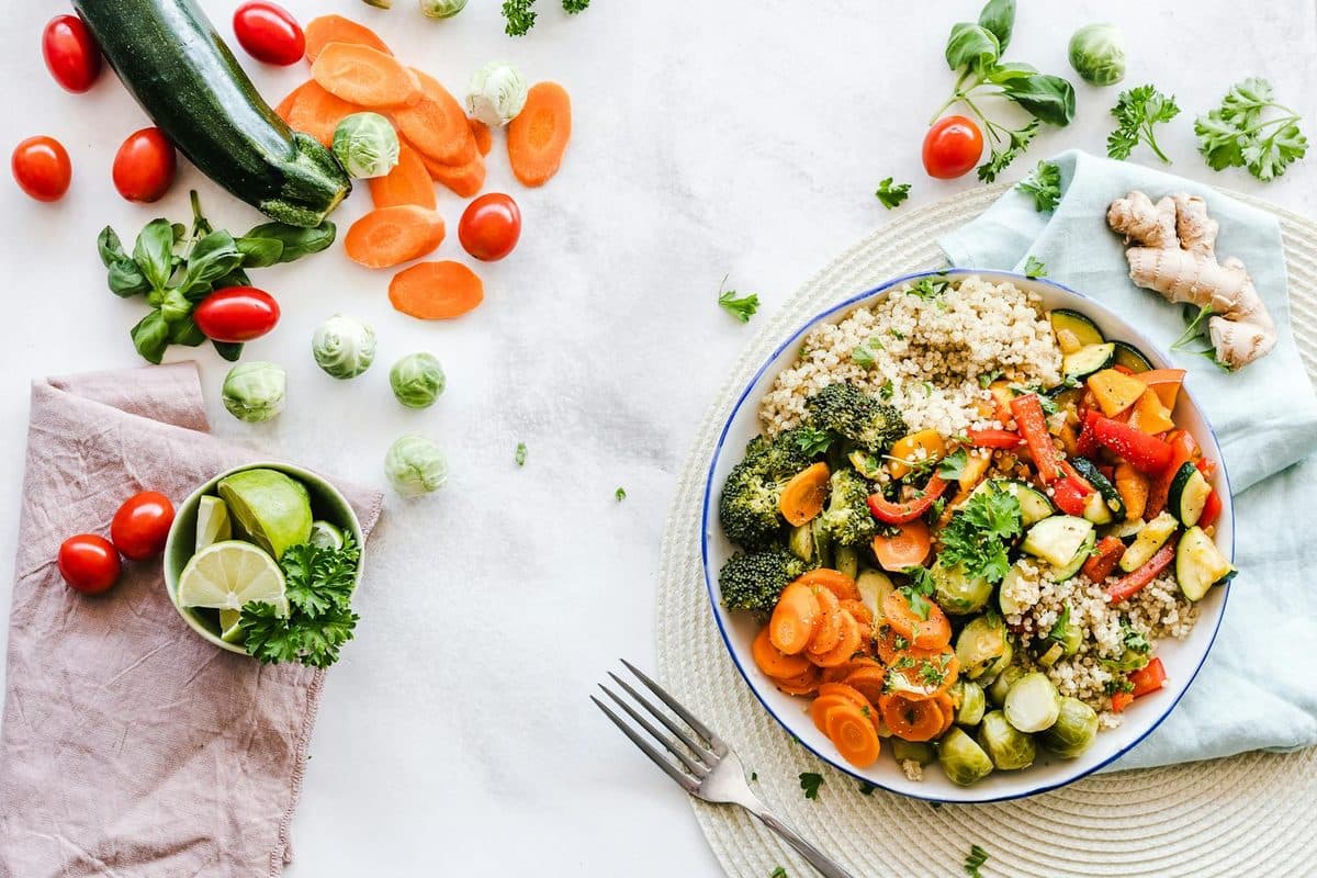 Prato colorido com legumes, grãos e proteína em uma mesa iluminada