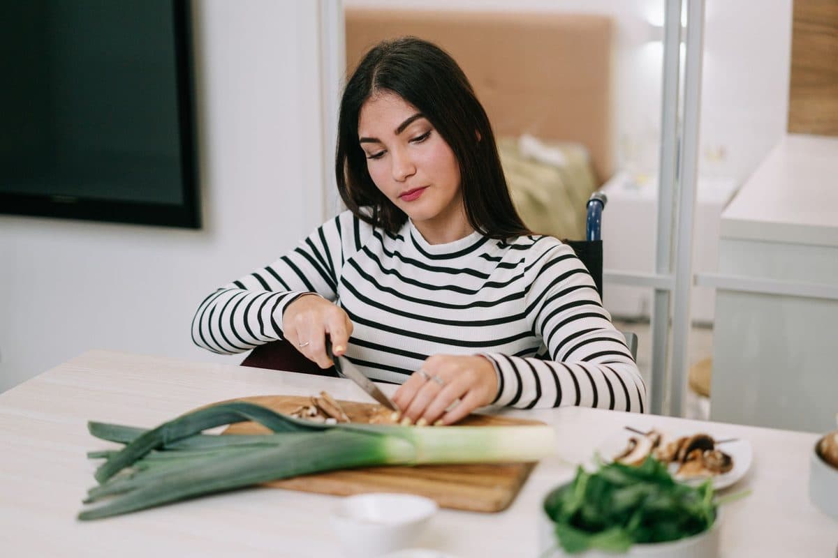 Mulher madura preparando uma refeição leve com vegetais frescos na cozinha